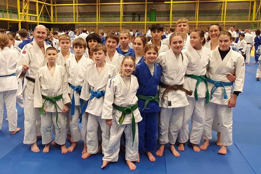 Gruppensicht von Judoka in weißen und blauen Kimonos auf einer blauen Matte in einer Turnhalle.